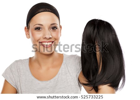 young woman with a wig cap on her head holding a wig in hand Royalty-Free Stock Photo #525733225