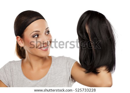 young woman with a wig cap on her head holding a wig in hand Royalty-Free Stock Photo #525733228