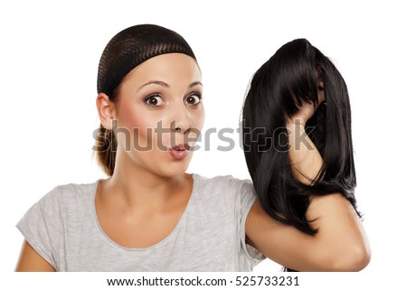 young woman with a wig cap on her head holding a wig in hand Royalty-Free Stock Photo #525733231