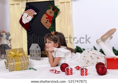 Beautiful little girl with gifts and decorations for Christmas evening and New Year

