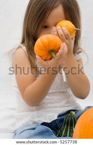 Little cute girl playing with fresh pumpkins