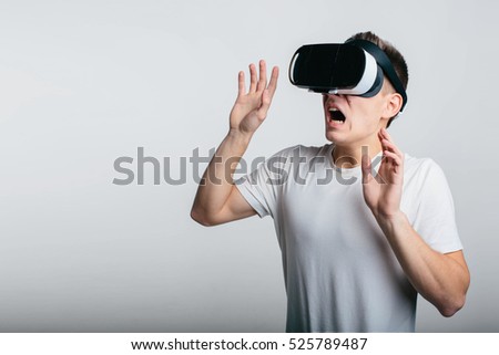 Man wearing virtual reality goggles. Studio shot, gray backgroun.