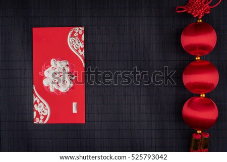 chinese knot and red envelope on black bamboo mat, flat lay, with copy space, character reads "fortune"