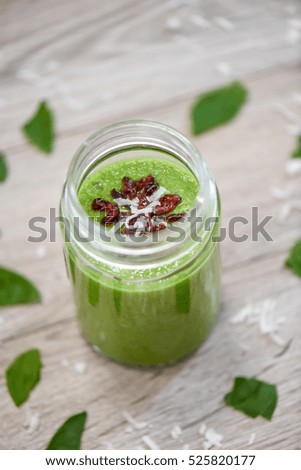green smoothies in glass with fruits and vegetables on table
