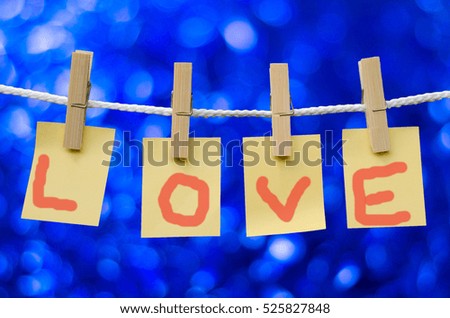 Clothespin with paper notes by writing "love".Bokeh blue background.
