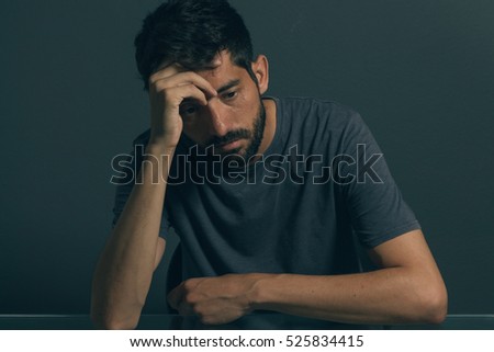 Sad man sitting in dark room. Depression and anxiety disorder concept Royalty-Free Stock Photo #525834415