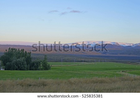  Moonrise with purple sky behind snow capped mountains in Iceland