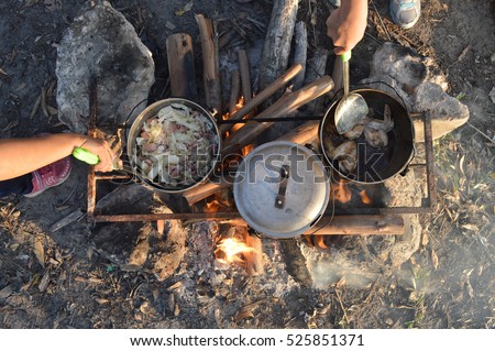 Cooking dinner on firewood stove. Cooking using firewood is an survival skill needed when going to the wilderness or outdoor activity. Royalty-Free Stock Photo #525851371