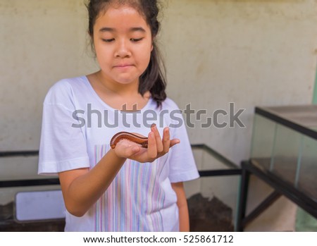 image of young asian girl hold Tropical spiral and many legs insect(millipede).