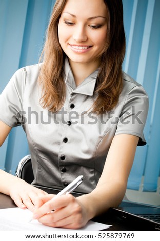Portrait of writing happy smiling businesswoman working at office