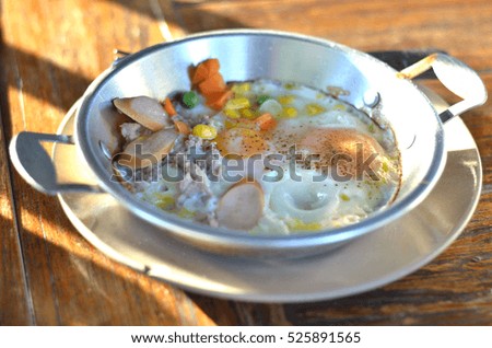 Fried eggs in pan with hot-dog and vegetable on wooden background.