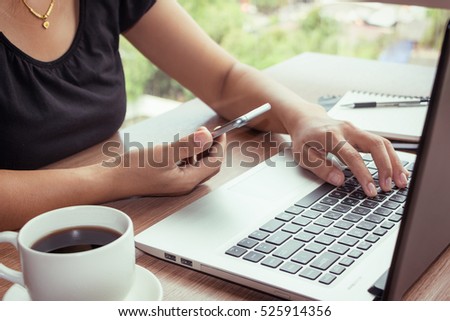 Close Up of woman hands using mobile phone and laptop computer with blank copy space screen for your advertising text message or content business in the Vintage effect.