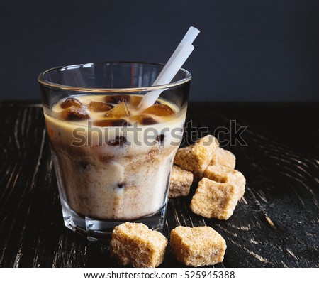 Milk with ice coffee and cane sugar on rustic background. Refreshment.