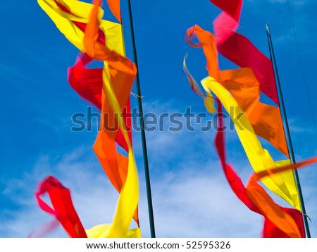 Red, Orange, and Yellow Flags Waving in a Blue Sky