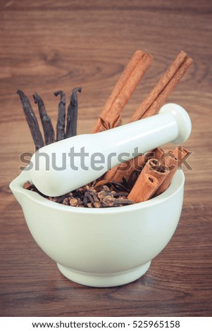 Vintage photo, Fragrant anise, cloves, cinnamon and vanilla sticks in white glass mortar on rustic wooden board