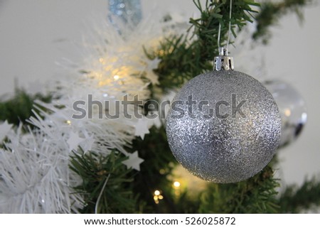 Silver Christmas or Xmas ball ornaments hanging on Christmas or pine tree branch in theme frozen.