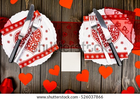 White card lies among white plates decorated for romantic dinner