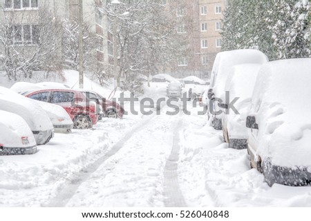 Snowstorm, snow-covered street and cars with a lonely pedestrian Royalty-Free Stock Photo #526040848