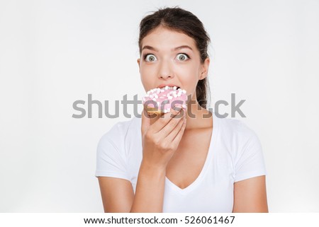 Picture of confused diet young woman eating tasty donut isolated over white background