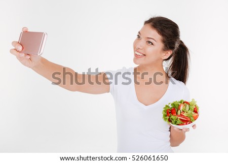 Happy young woman take a selfie with vegetable salad. Isolated on white background.