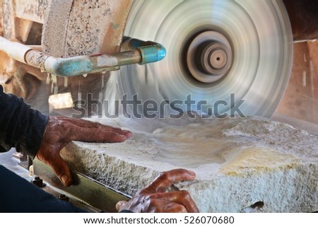 close up hand of stone mason cutting sandstone by industrial circular saw blades Royalty-Free Stock Photo #526070680
