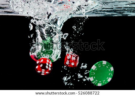 Red dice and chips in the water on black background. Visible splash and air bubbles.