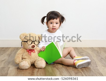 Child little asian girl reading a book in the white background with a toy teddy bear, Baby healthy and preschool concept
