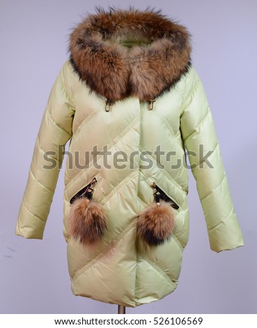 Winter down jacket isolated on grey background. Lime down jacket on dummy without face. Outerwear. Lime coat. Cloth. Down jacket. Nobody.