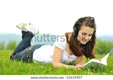 Beautiful teenager reading a book in nature