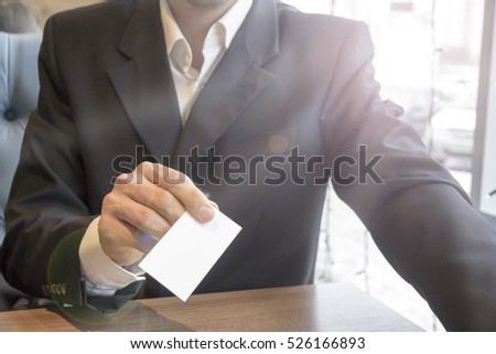 A man in a business suit holding a business card mockup