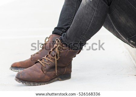 Men fashion in leather boots, Close up view on man's legs in black jeans and brown leather boots, Toned picture.