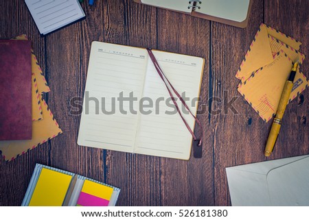 Notebook with envelopes and pen on a wood table.Top view