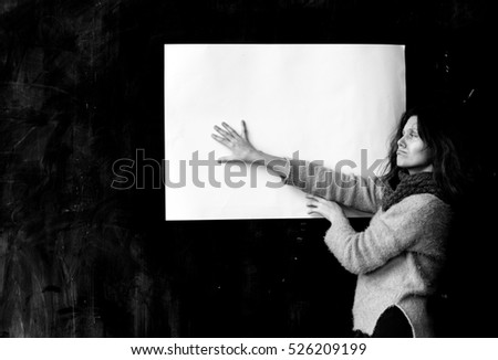 The girl is holding a white paper, a sad student near the blackboard is meditating.