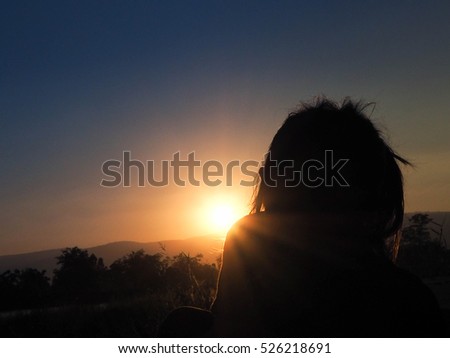 Sunset with silhouettes of female children in the holidays.
She was happy to sit back and enjoy the sun.
Sky gold bright