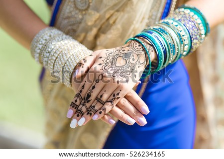 mehendi on the hands of girls,Woman Hands with black mehndi tattoo. Hands of Indian bride girl with black henna tattoos. Hand with perfect turquoise manicure and national Indian jewels. Fashion. India