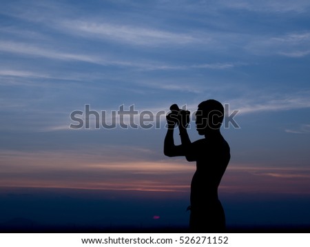 Silhouette of a man taking a picture in twilight time