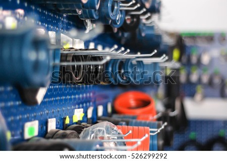 Auto and heavy vehicles store shelf with assortment of colorful rubber gaskets hanging from a blue wall rack. Depth of field bokeh effect. Royalty-Free Stock Photo #526299292
