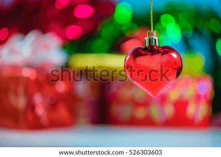 Christmas heart shaped red ball and blurred Christmas decorations box with bokeh background.