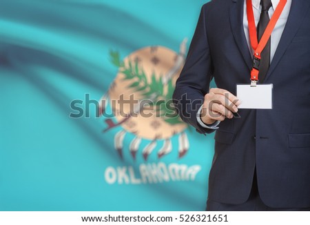 Businessman holding name card badge on a lanyard with US state flag on background - Oklahoma