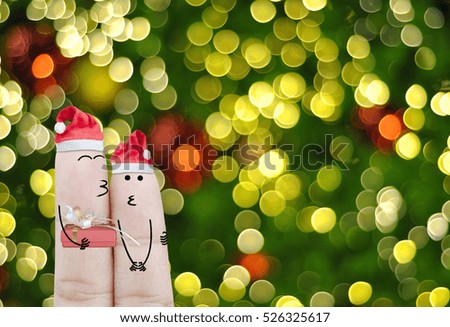 Couple finger with hat santa claus and gift on hand with bokeh light, holiday christmas art abstract background
