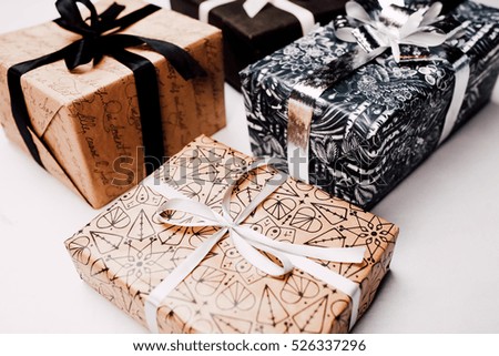 Christmas gift boxes composition. white background, white, silver and black ribbons and craft and black paper