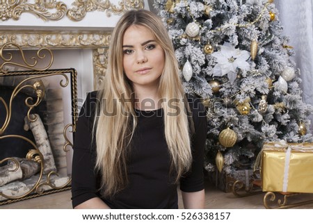 The pretty girl next to the fireplace and Christmas tree