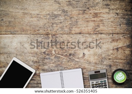 Wooden table with notepad, computer and green tea cup. View from above with copy space