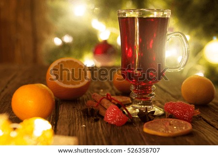 Christmas mulled wine on wooden table over defocused christmas tree background. Toned picture. Mulled wine on wooden table. Hot Mulled Wine with orange.