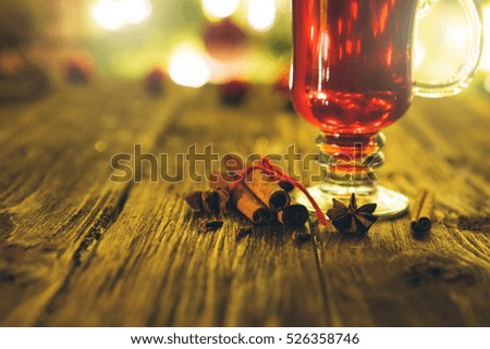 Single glass of hot mulled on defocused christmas tree background. Mulled wine on wooden table. Hot Mulled Wine with orange.