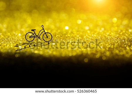 Silhouette of a bicycle on gold sparkling Glitter bokeh Background.