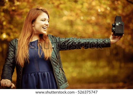 Beauty makeup nature forest autumn concept. Ginger girl taking selfie. Young attractive redhead lady takes picture of herself.