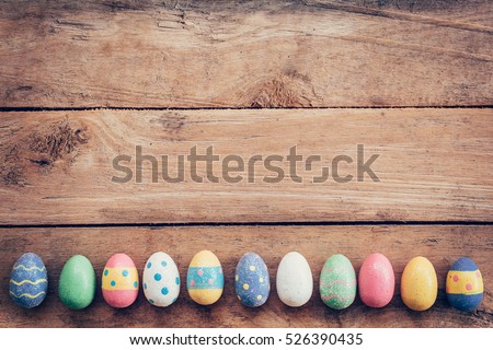 Colorful pastel easter eggs on wooden board background with space. Vintage toned.