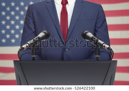 Businessman or politician making speech from behind the pulpit with USA flag on background