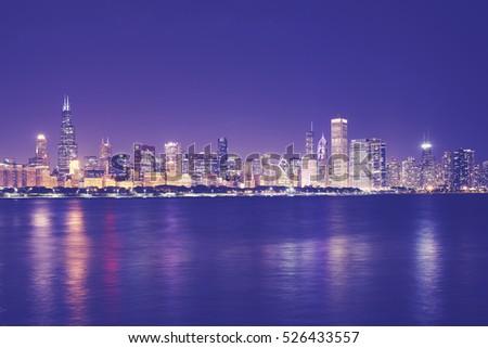 Vintage toned picture of Chicago city skyline with reflection in Lake Michigan at night, USA.